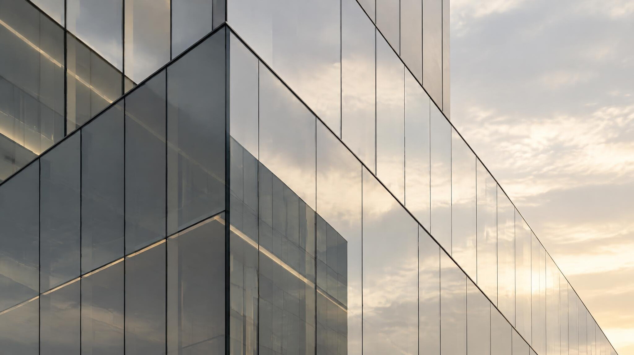 Glass office building facade with soft reflections of sky