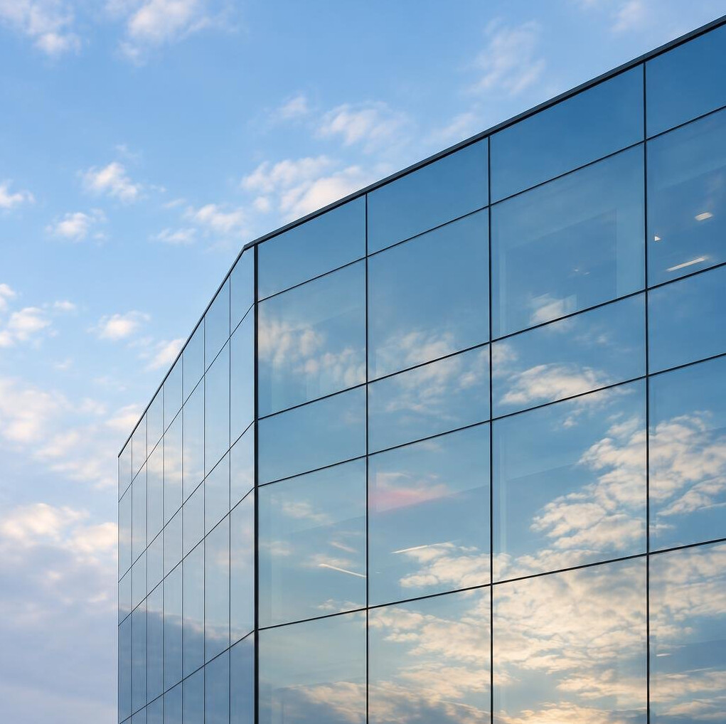 Modern glass building facade reflecting the sky