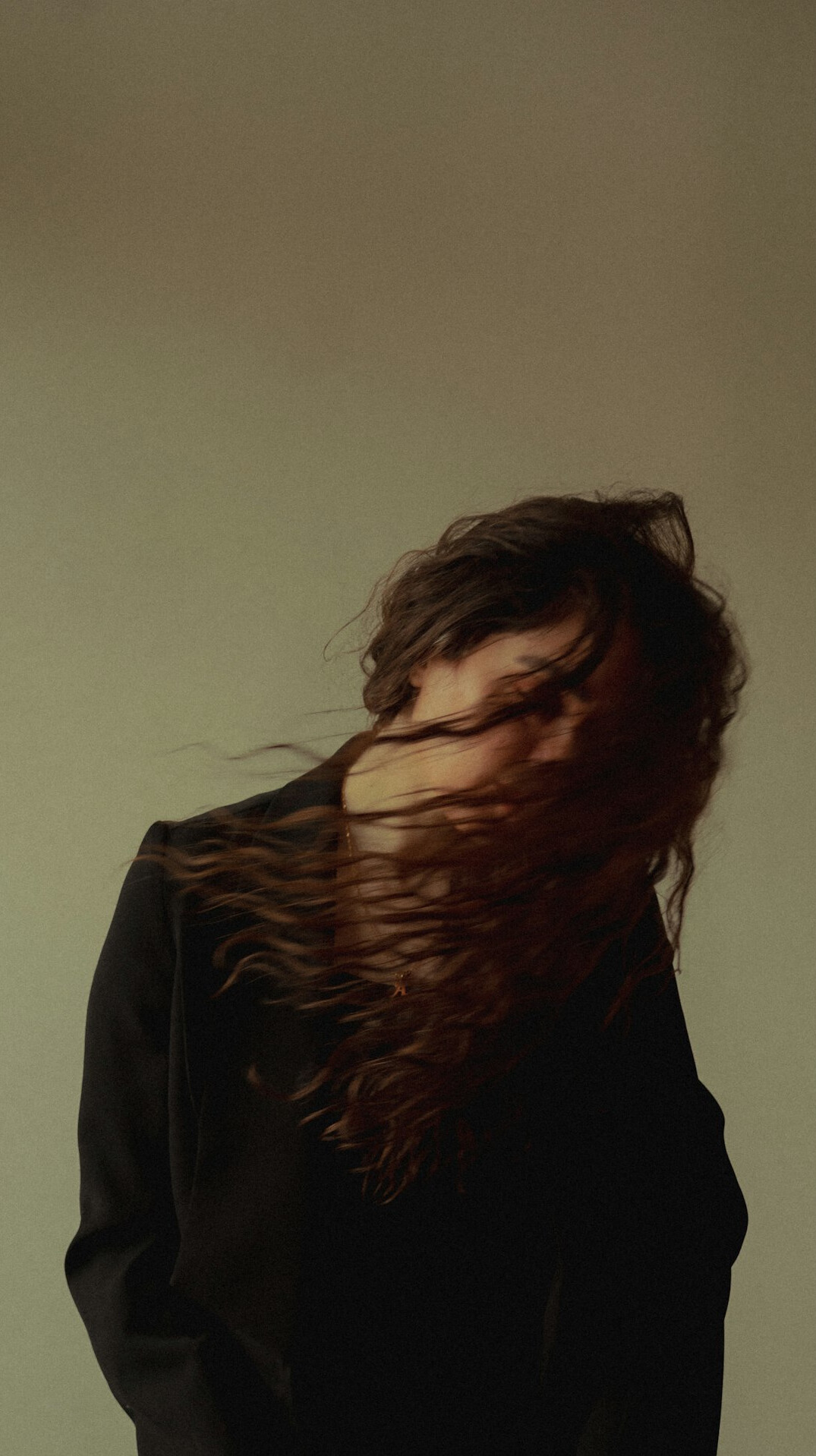 Portrait of a woman with shoulder-length brown hair in a dark blazer against a neutral background